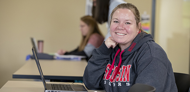 Student sitting at desk smiling at the camera